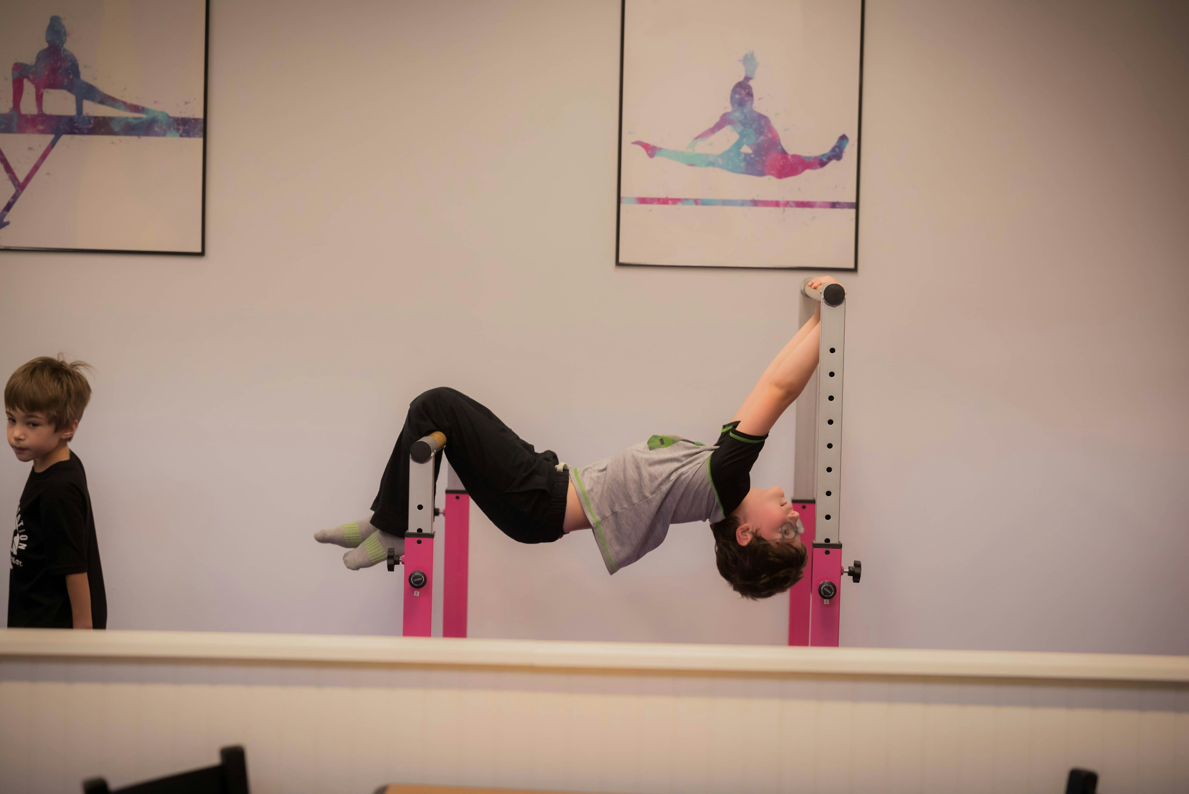 Hanging from the bars in the gymnastics room.